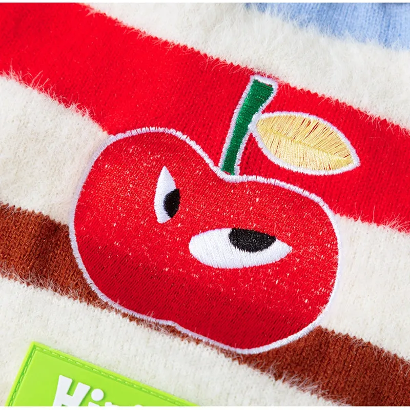 Corgi dog wearing a rainbow apple striped knitted pullover sweater in brown, standing on grass