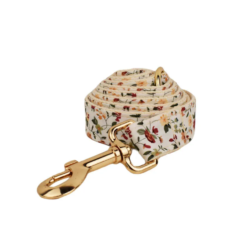 Small white flower pattern dog collar set with matching leash, vest, and bow on a mannequin.