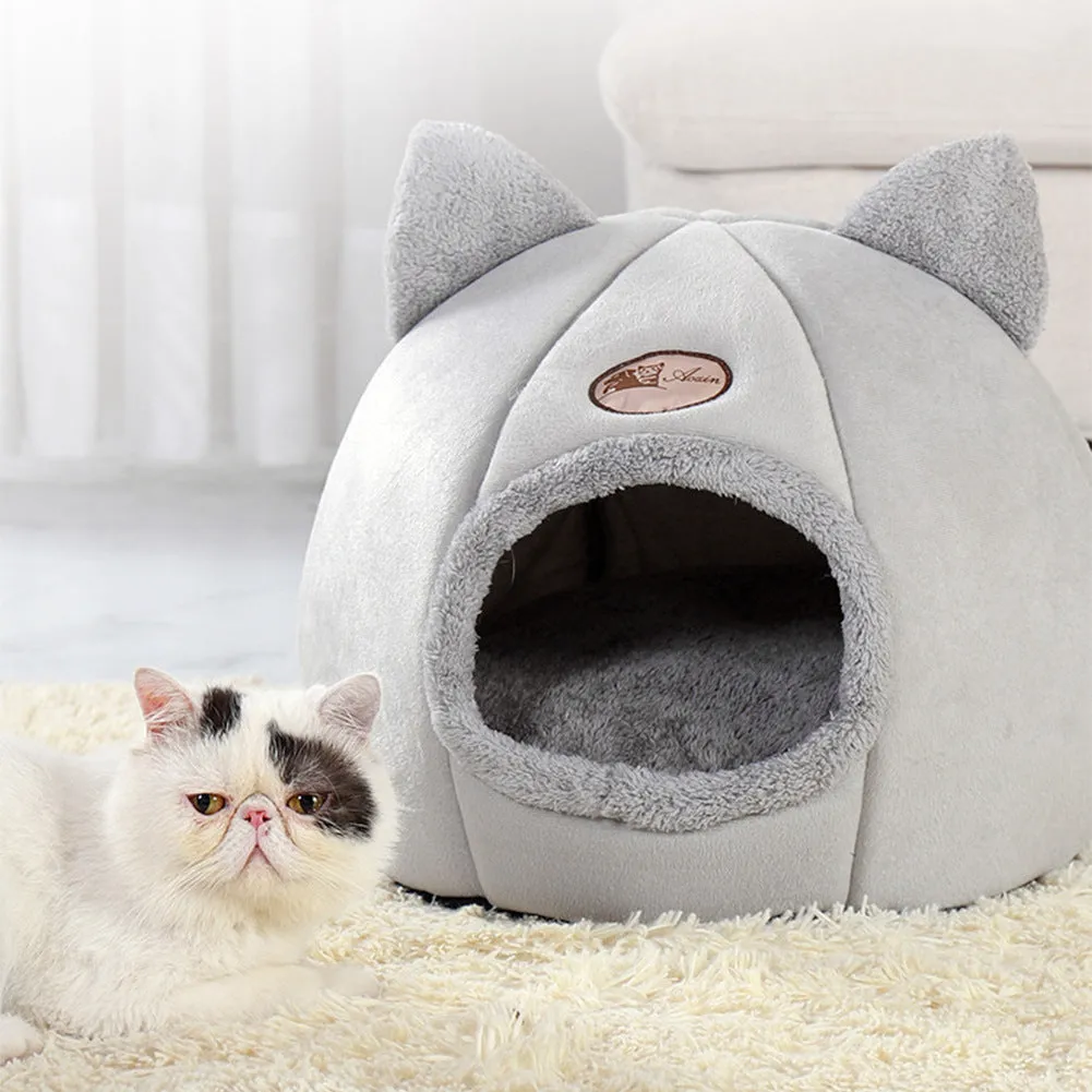 A large fully enclosed sofa-shaped cat winter house with a removable fleece cushion inside, shown in a home setting.
