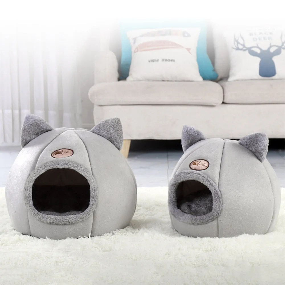 A large fully enclosed sofa-shaped cat winter house with a removable fleece cushion inside, shown in a home setting.