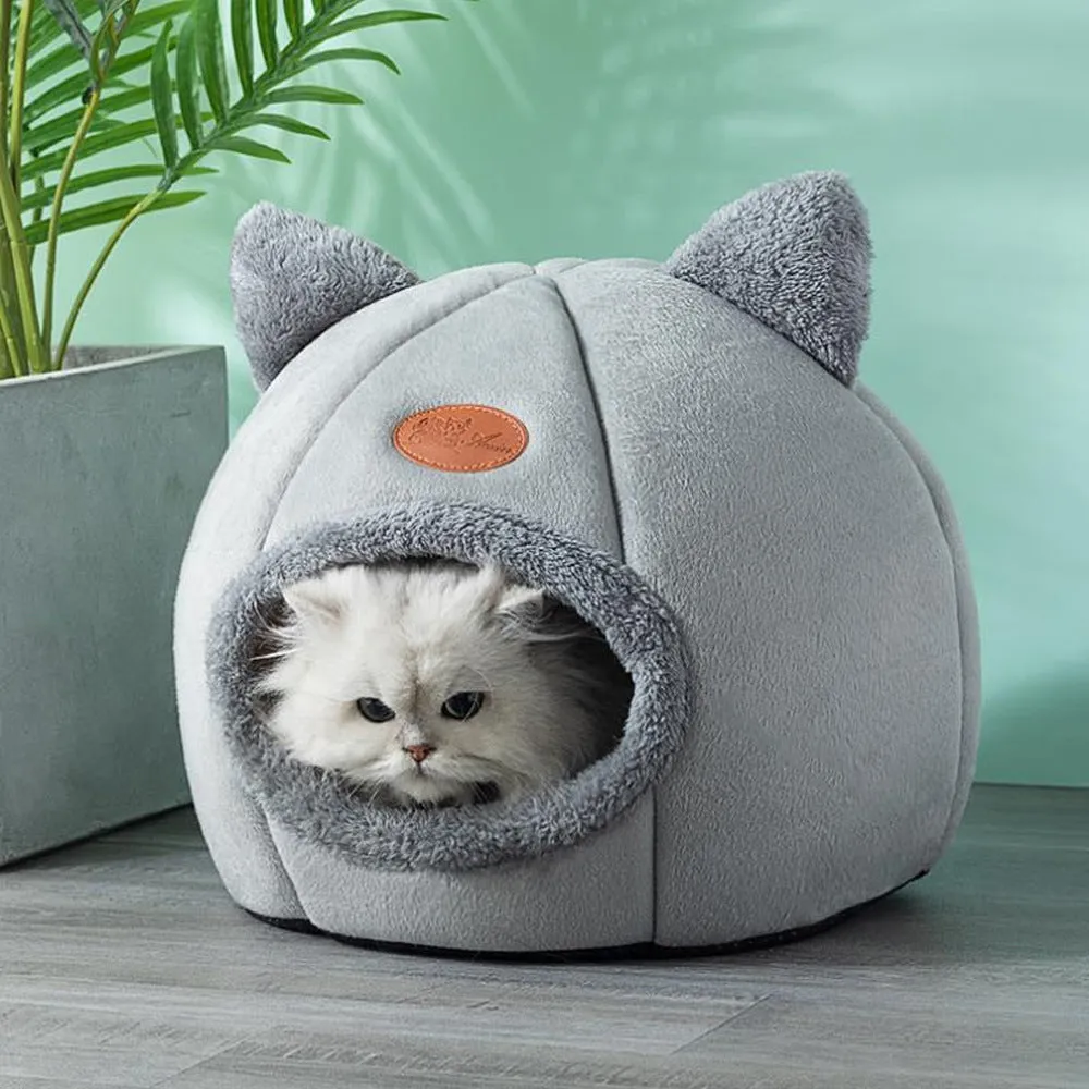 A large fully enclosed sofa-shaped cat winter house with a removable fleece cushion inside, shown in a home setting.
