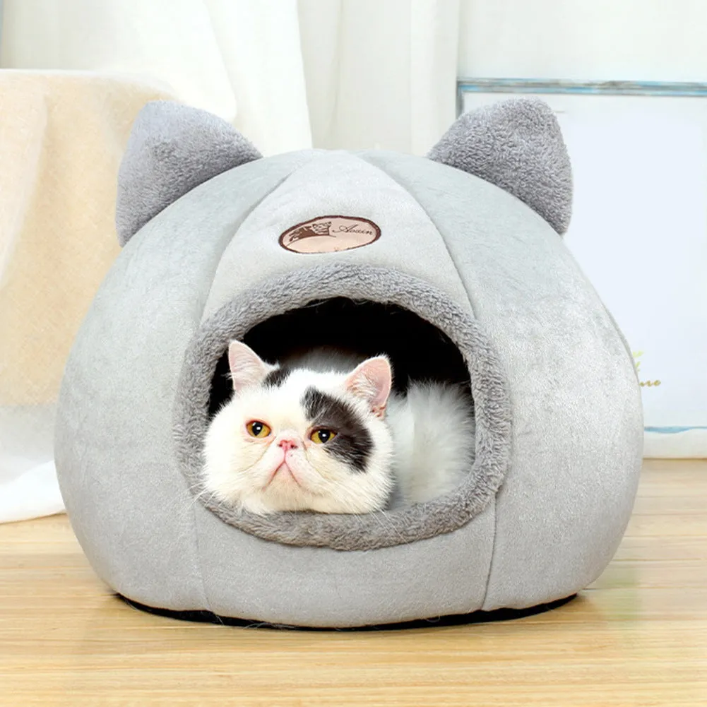 A large fully enclosed sofa-shaped cat winter house with a removable fleece cushion inside, shown in a home setting.