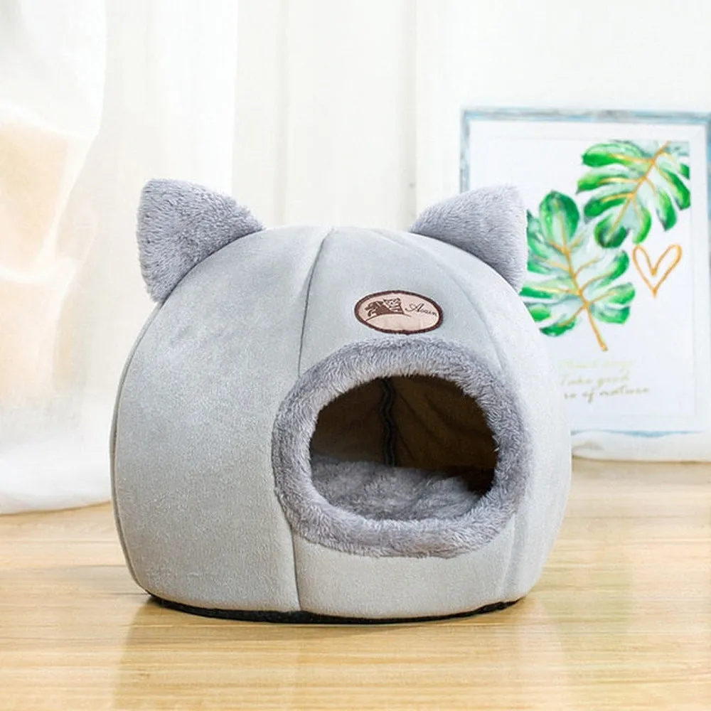 A large fully enclosed sofa-shaped cat winter house with a removable fleece cushion inside, shown in a home setting.