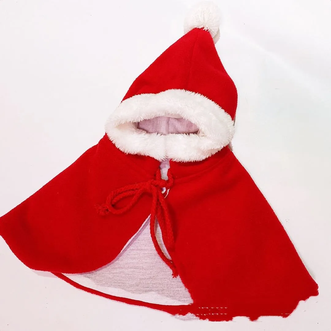 Red Christmas shawl cloak on a small dog with green background.