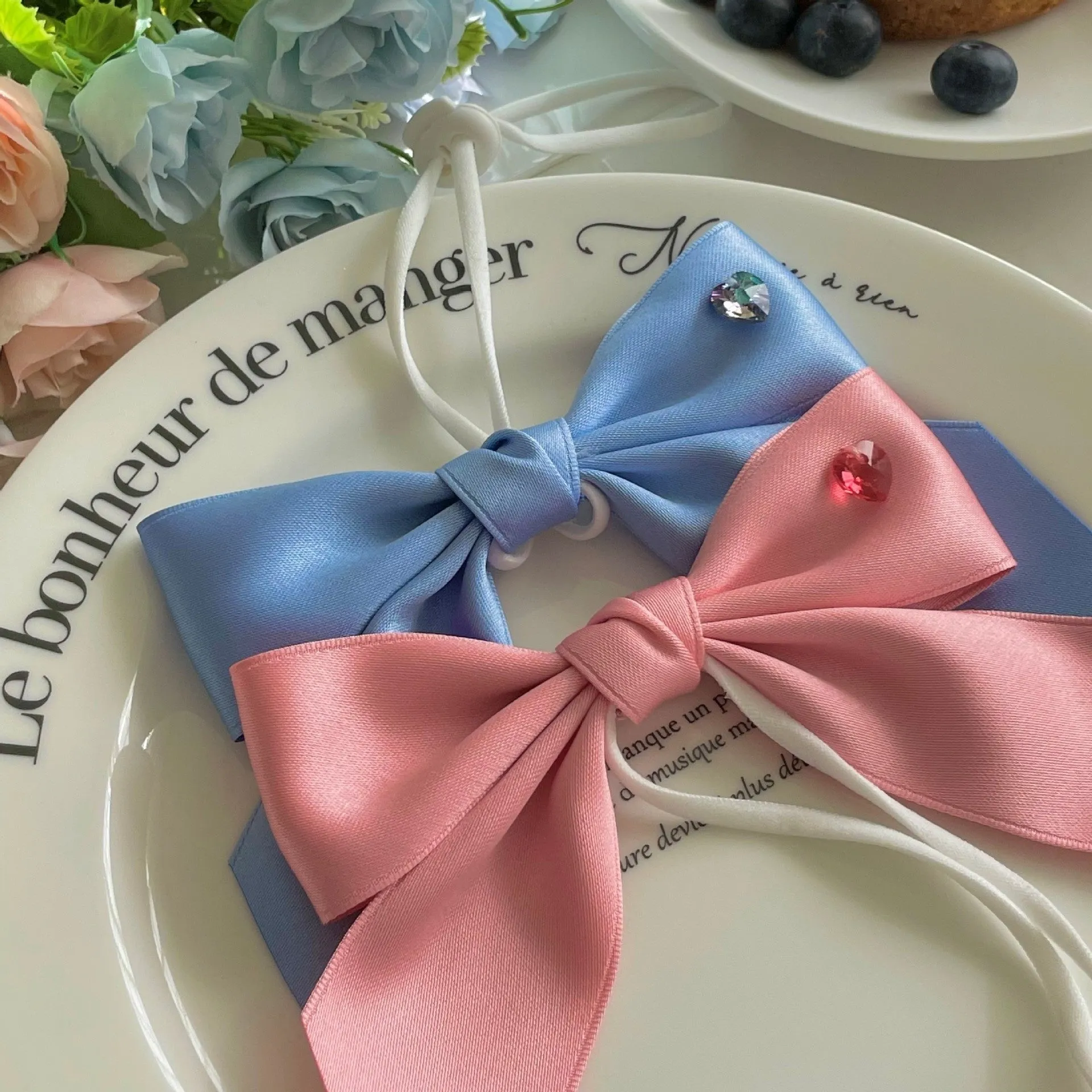 Blue princess-style adjustable bow hair band for dogs on a white background.