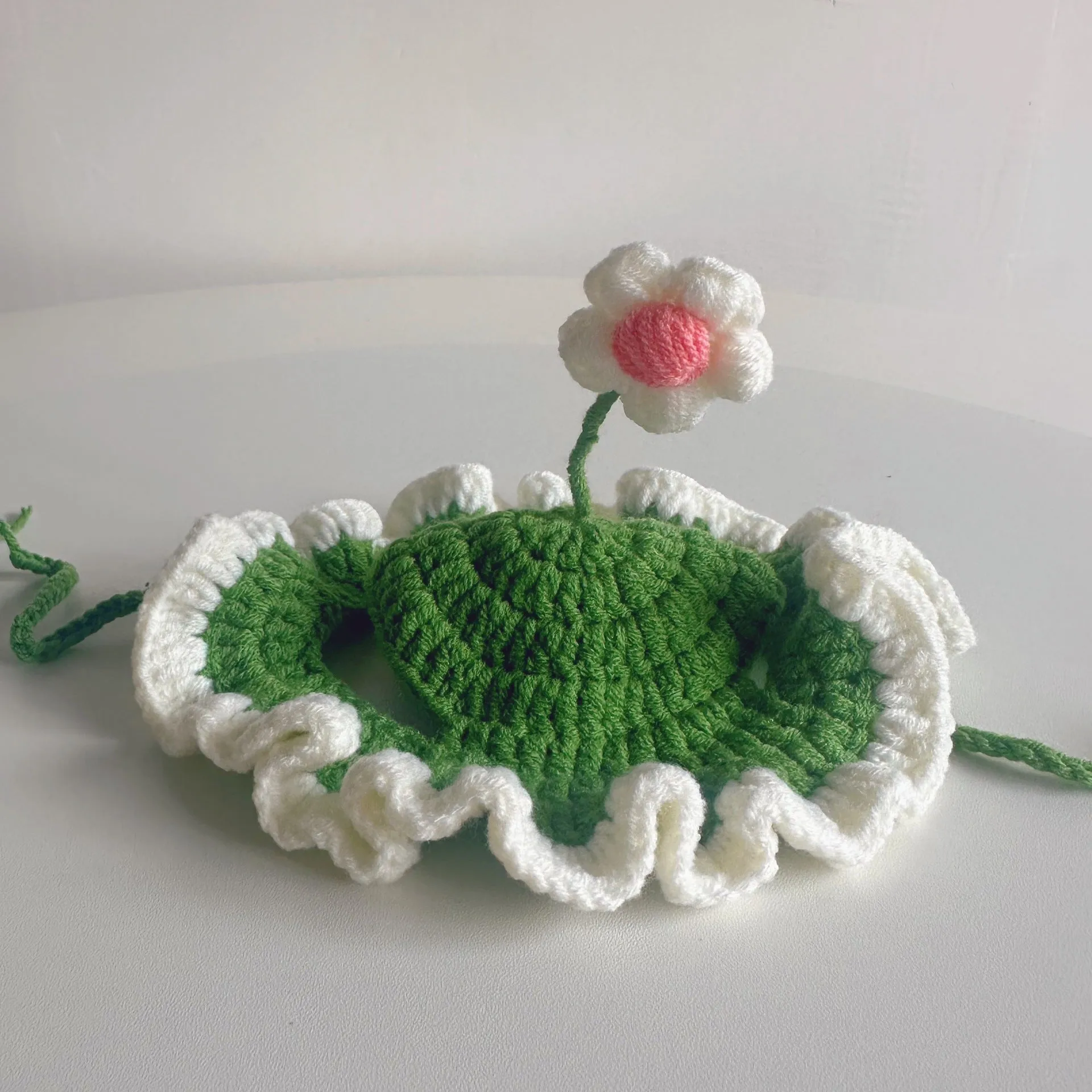 Green knitted cartoon cat hat on a pet mannequin head showing soft fabric and costume design.