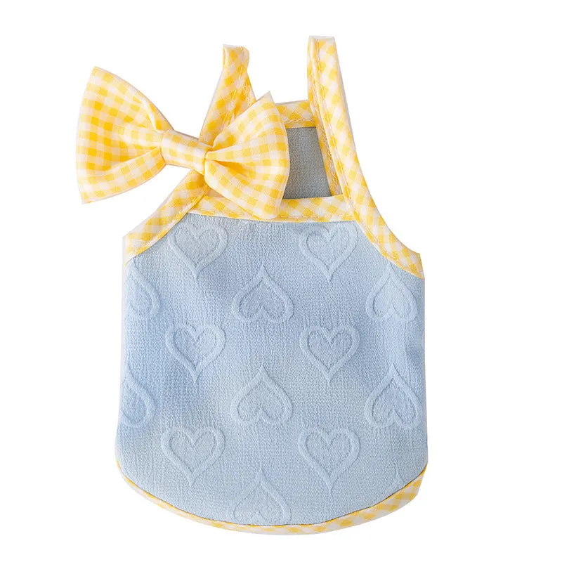Small dog wearing a blue vest with a heart relief texture and white bow suspenders.