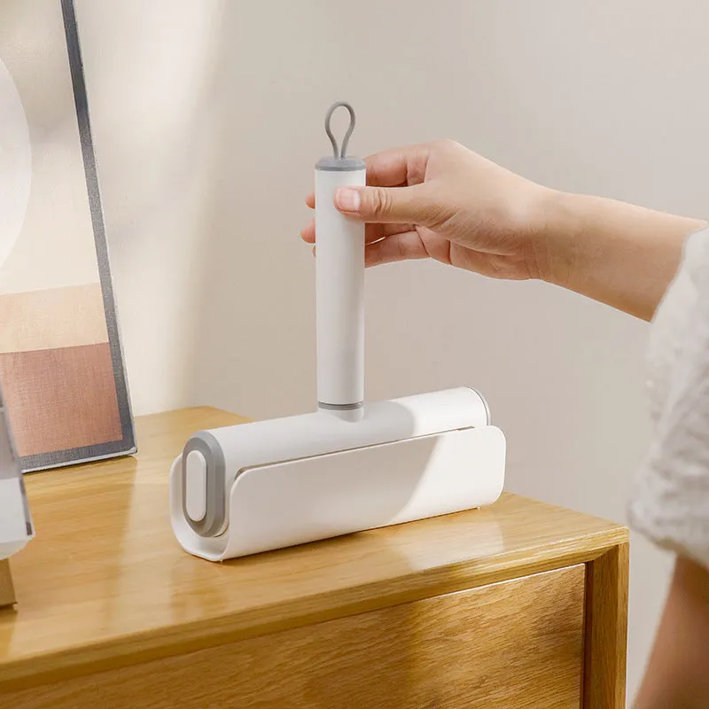 Handheld lint remover roller for pet hair removal on floors with tearable paper stick.