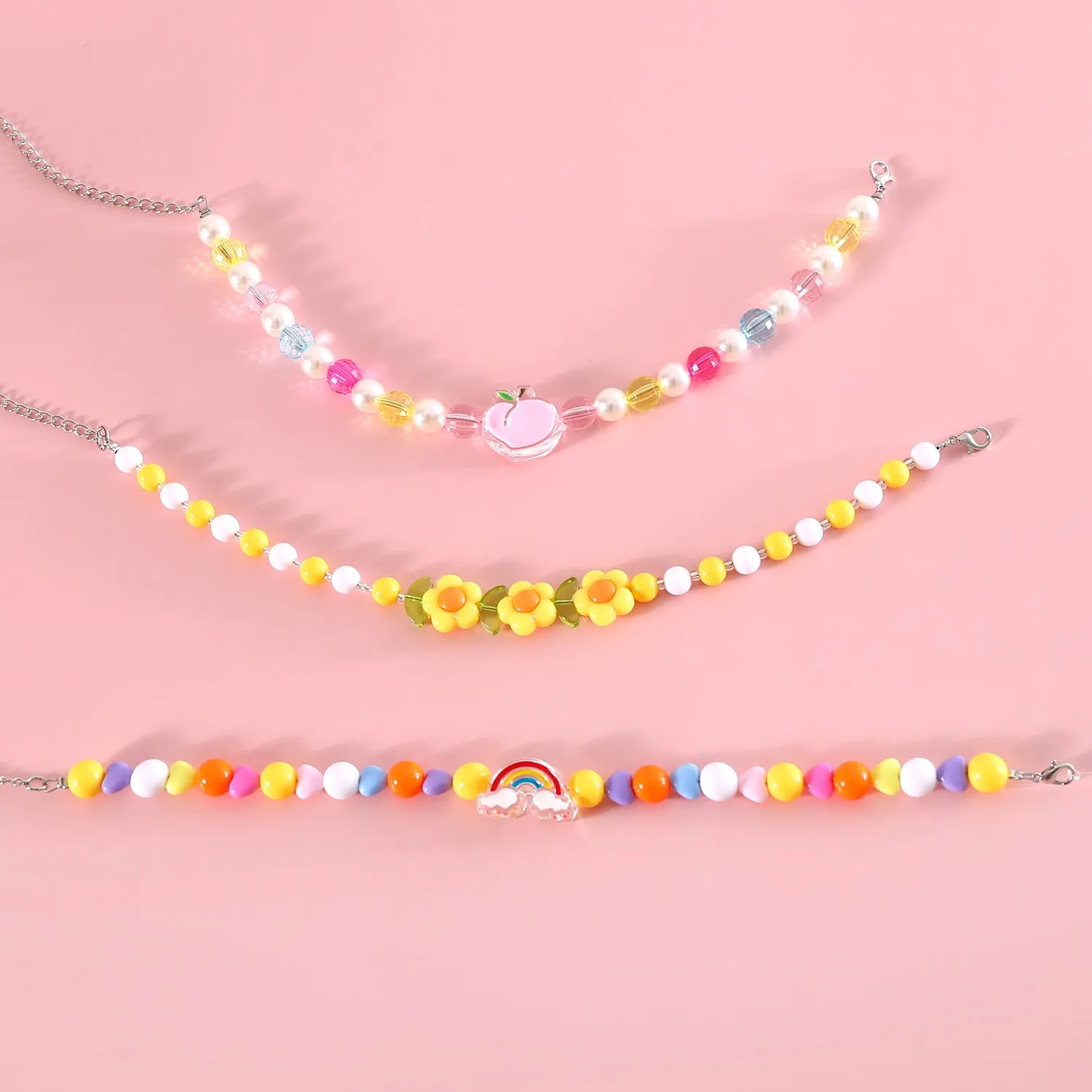 Colourful plastic pearl necklace for small pets on a white background, showing peach, rainbow, and small flower bead design options.