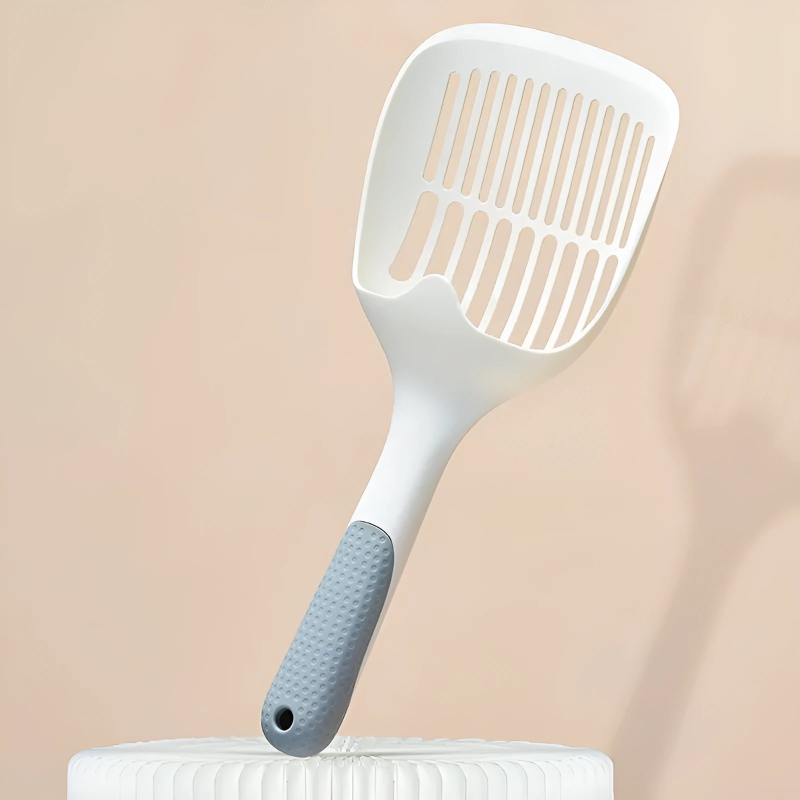 White plastic cat litter scoop with storage base for containing tool between uses