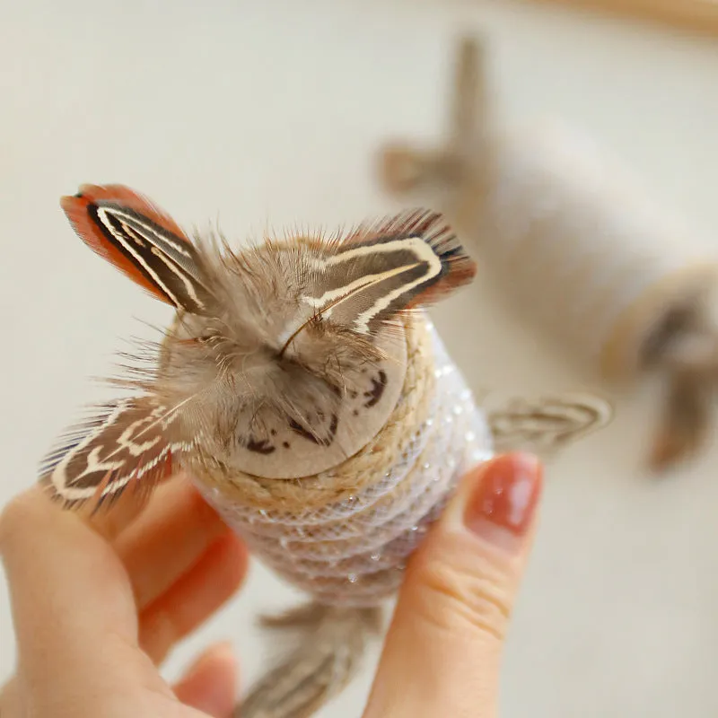 Beige cat toy with real feathers attached to hemp rope scratching surface and integrated claw roller