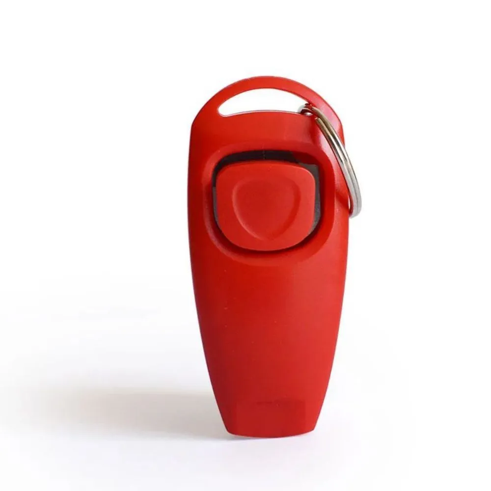 Pet training clicker and whistle set with key ring in orange, white, and blue plastic on a wooden table