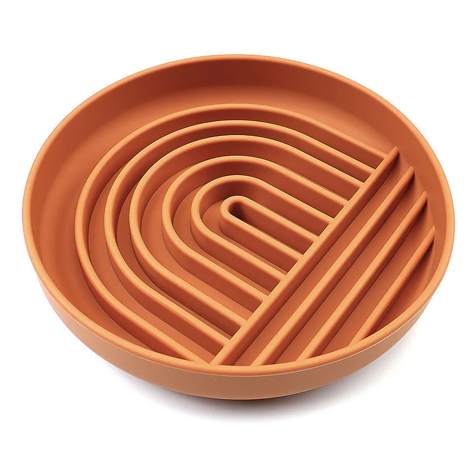 Silicone slow feeder dog bowl with ridges in various colours on a table.