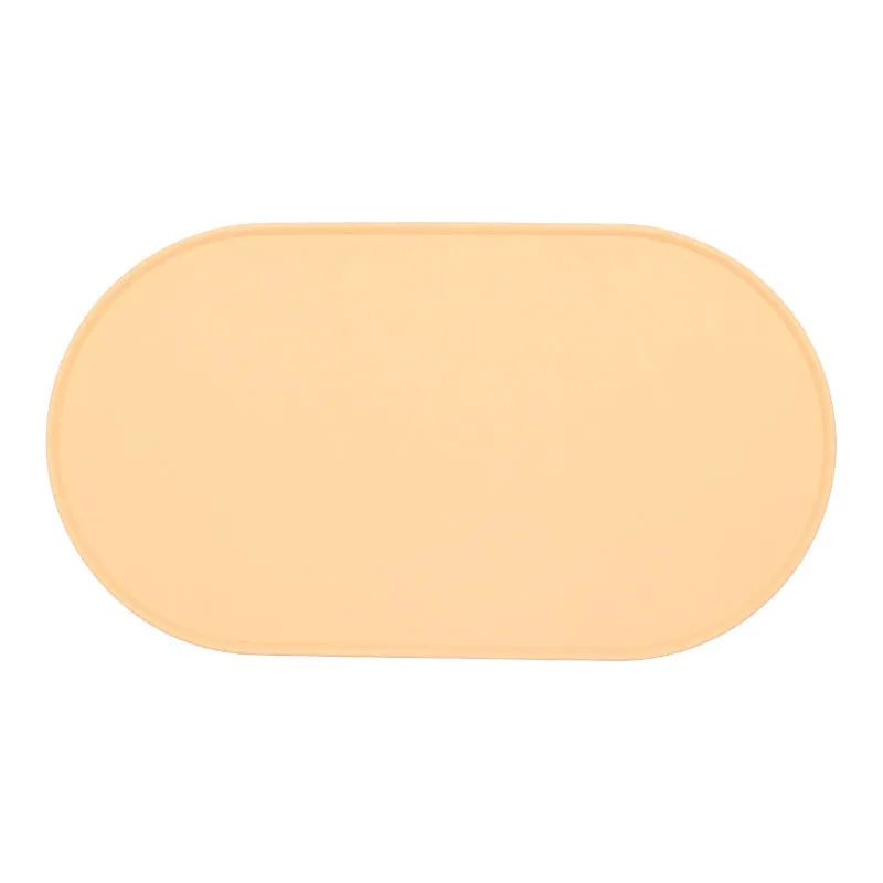 Silicone waterproof cat feeding placemat in beige colour on a floor next to a food bowl.