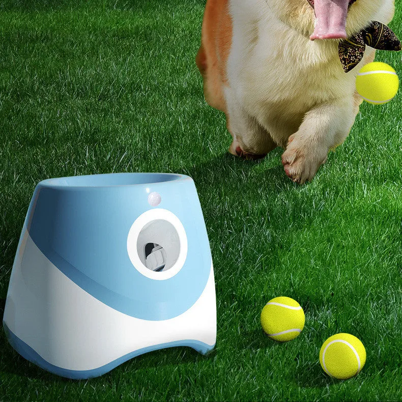 Blue automatic ball thrower with thermal sensor, three tennis balls, and USB charging cable on grass