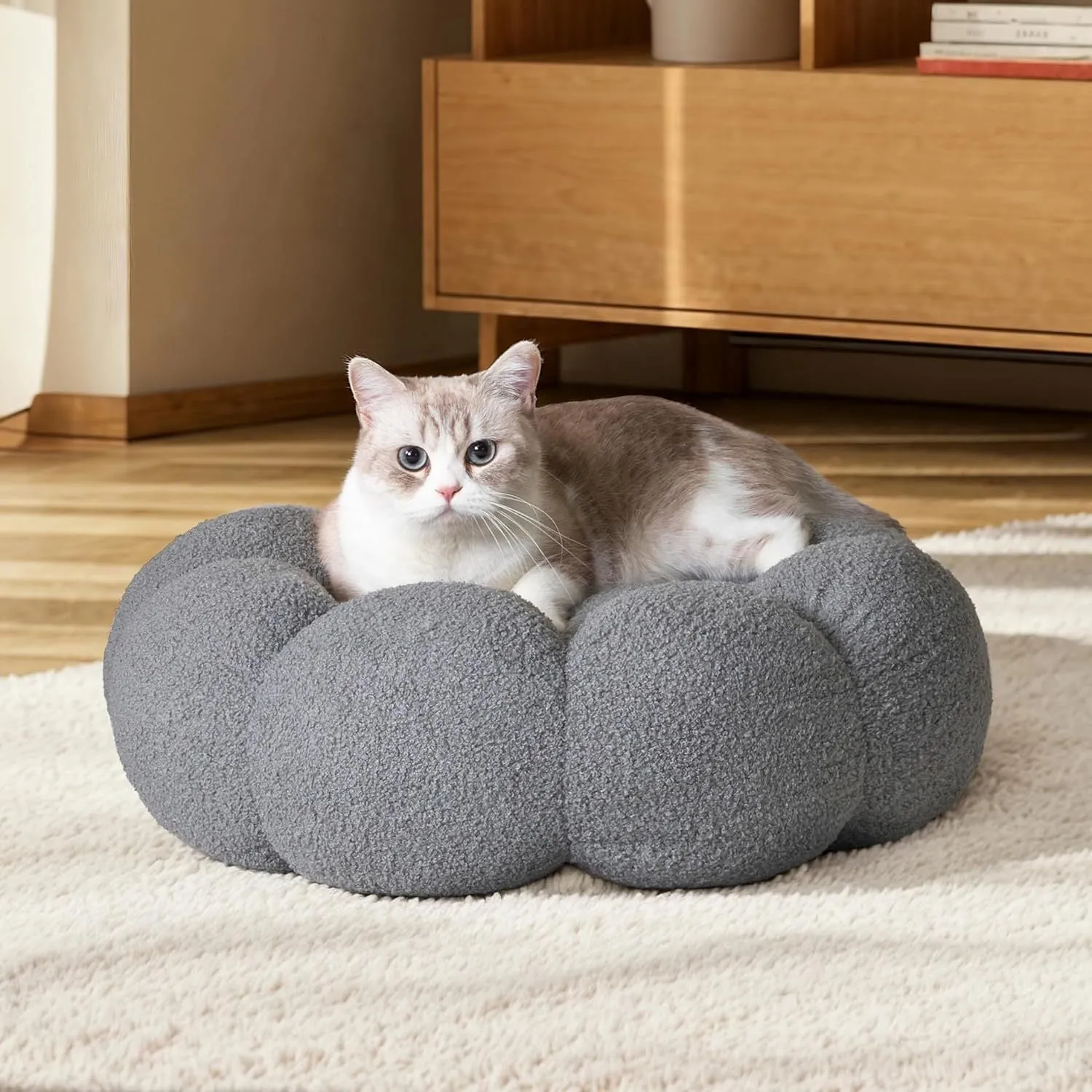 White fluffy flower-shaped pet bed with raised teddy fleece edges and round donut design on a light floor