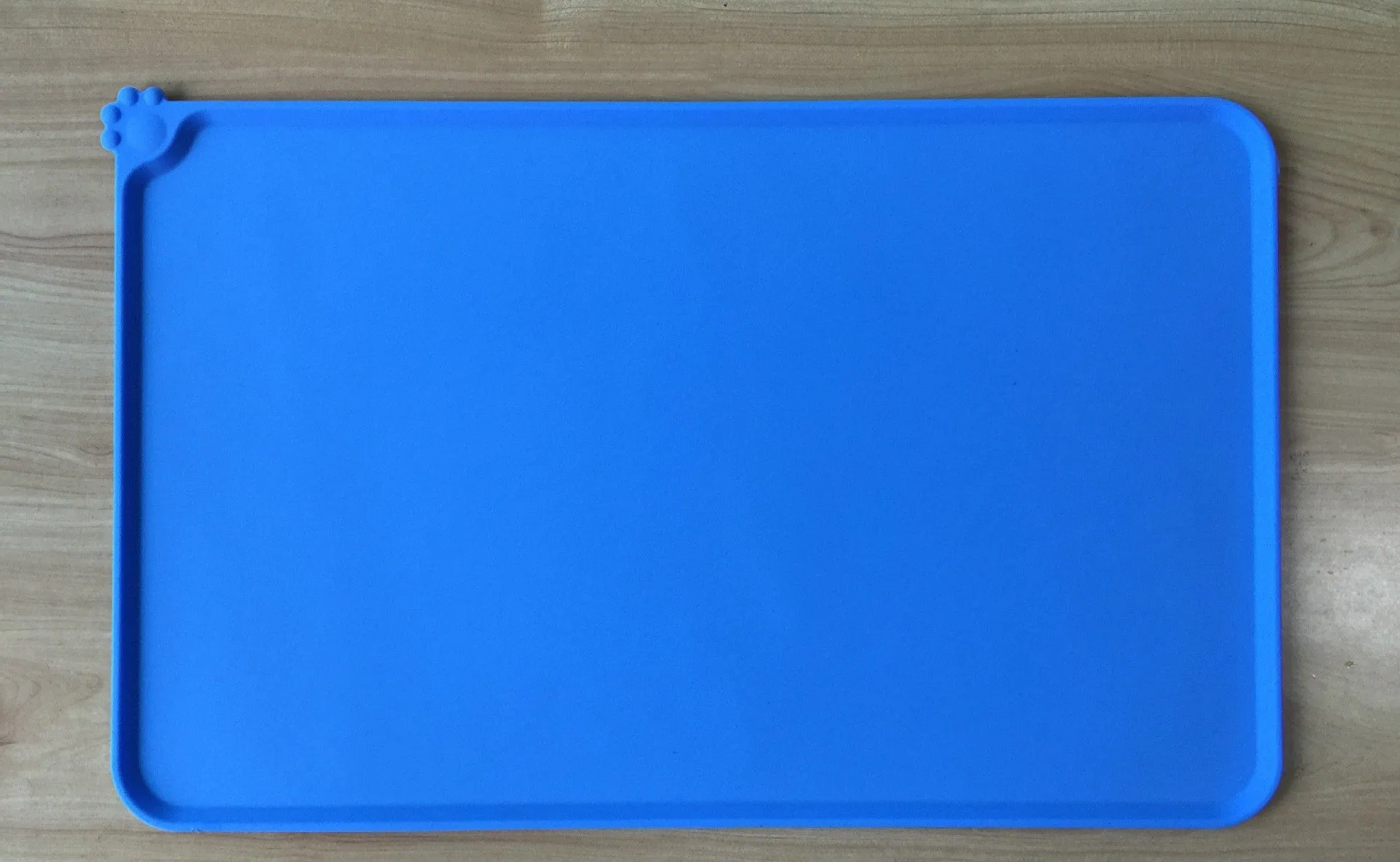 Black silicone dog food mat measuring 47 by 30 centimetres with non-slip surface and raised edges.