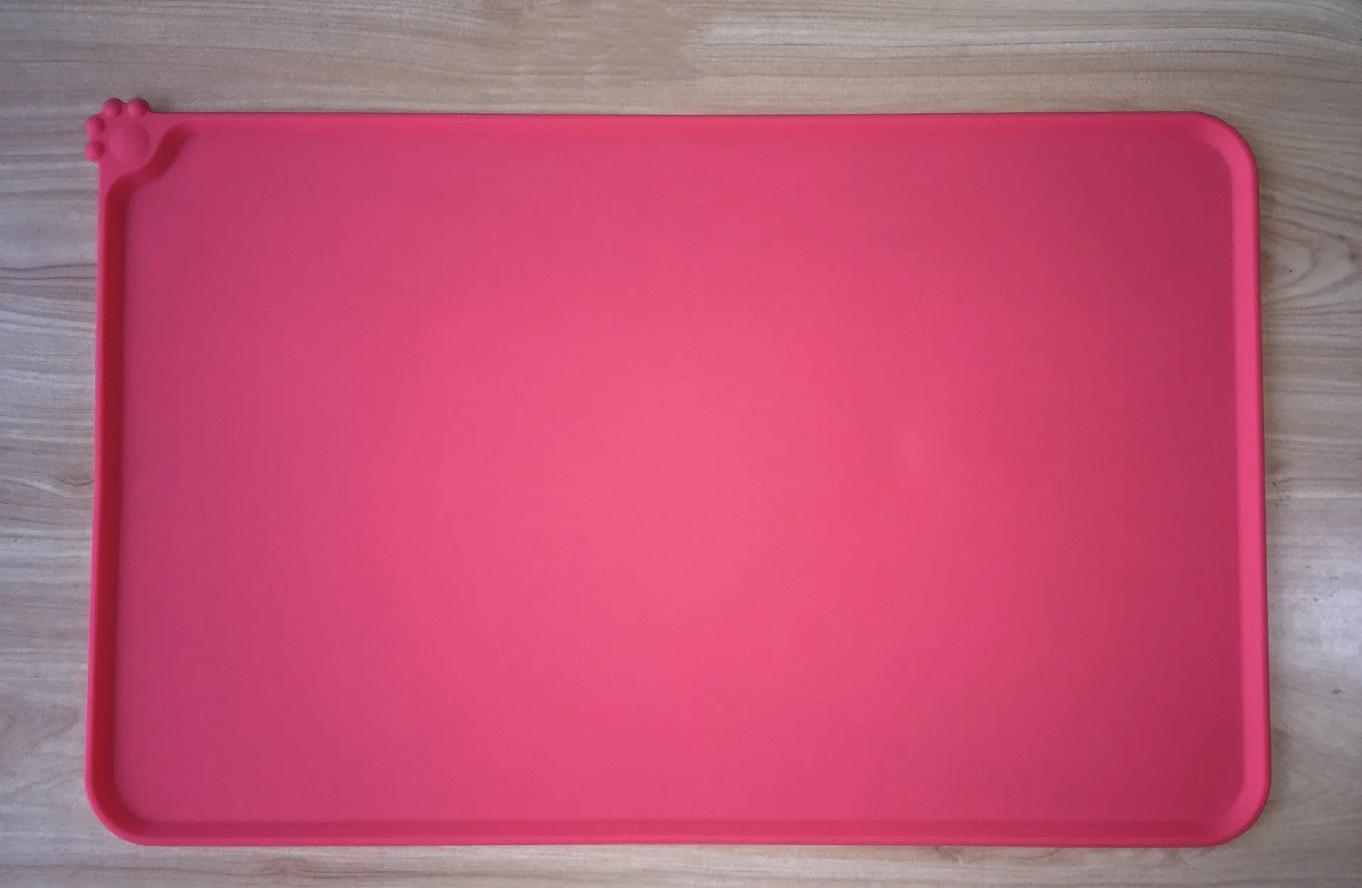 Black silicone dog food mat measuring 47 by 30 centimetres with non-slip surface and raised edges.