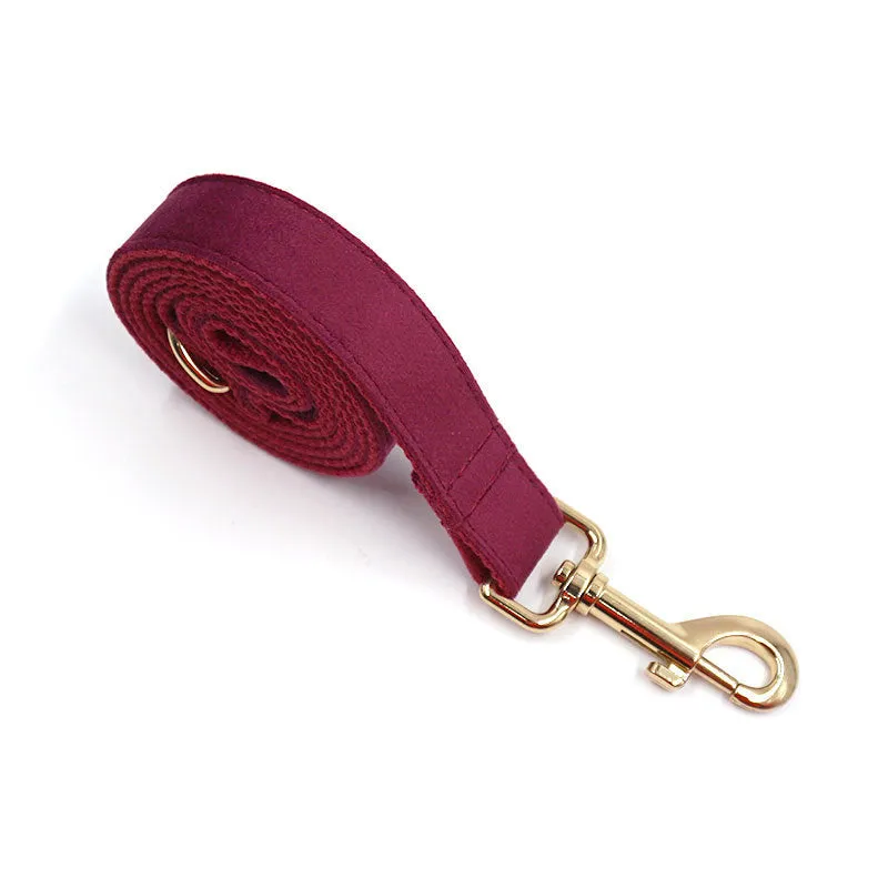 Burgundy velvet dog collar set with bow tie and leash on a wooden floor