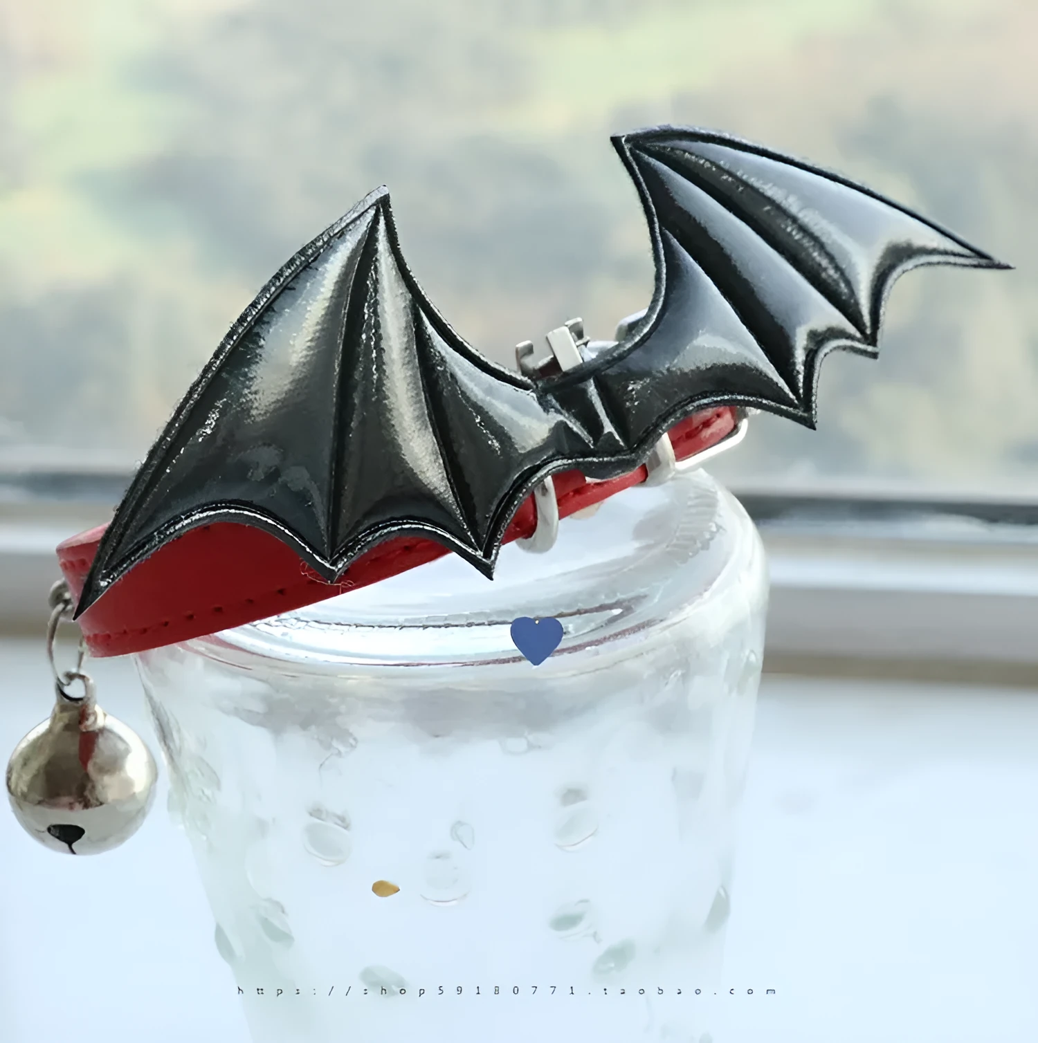 Small black patent leather choker collar with attached devil wings and a bell.