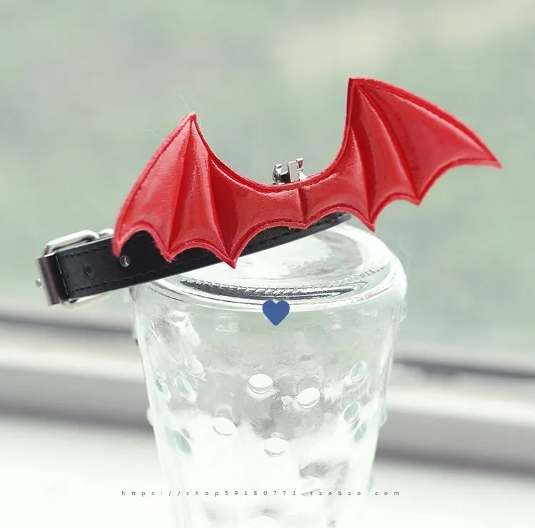 Small black patent leather choker collar with attached devil wings and a bell.