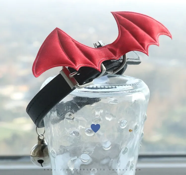 Small black patent leather choker collar with attached devil wings and a bell.