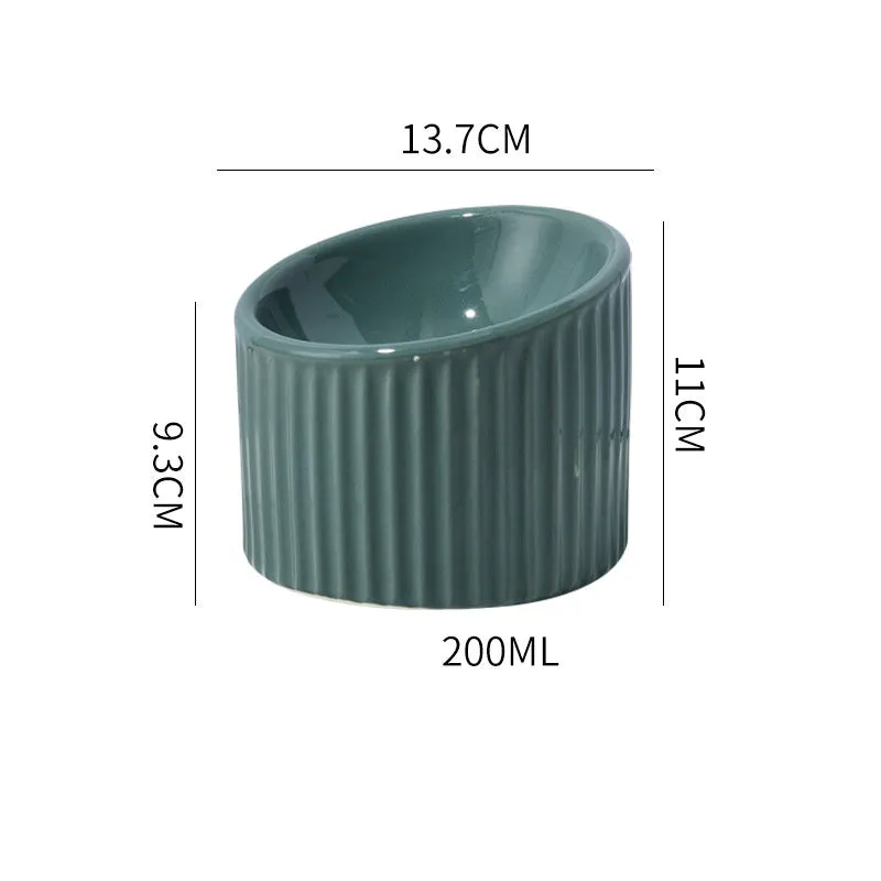 Dark green ceramic elevated cat bowl with tilted, round design on a wooden floor.