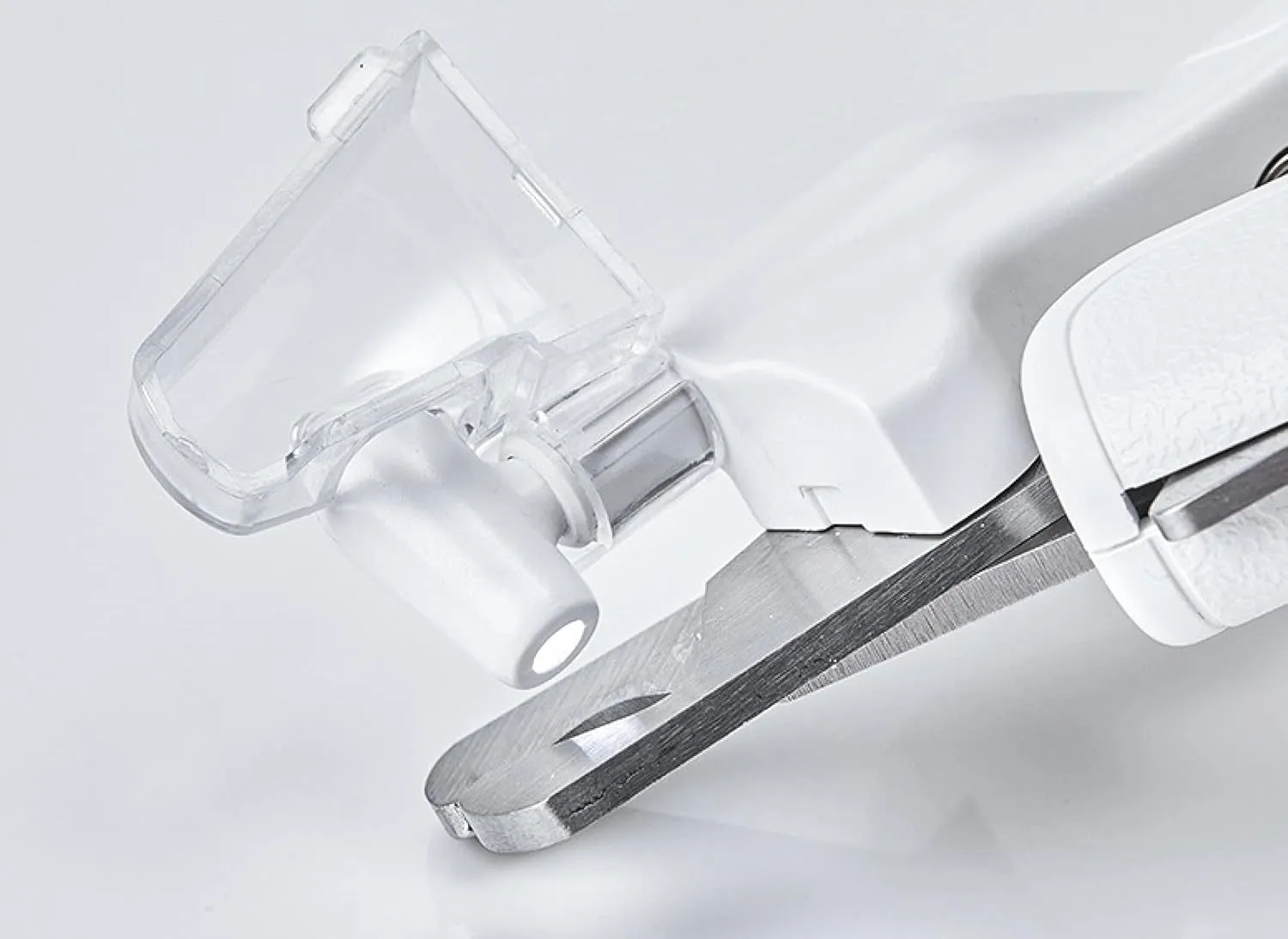 White pet nail clippers with LED light and transparent anti-splash guard next to a nail file on a table