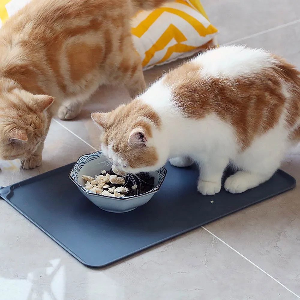 Grey waterproof silicone pet mat with raised edges and a non-slip base, measuring 47x29.5cm, placed under two pet bowls
