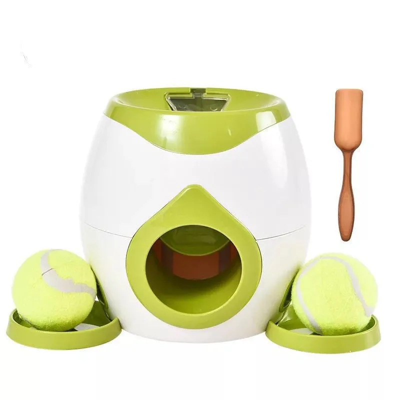 Smart pet feeder reward machine with two tennis balls and treat dispenser in green and white colour, shown on a wooden floor