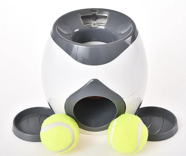 Smart pet feeder reward machine with two tennis balls and treat dispenser in green and white colour, shown on a wooden floor