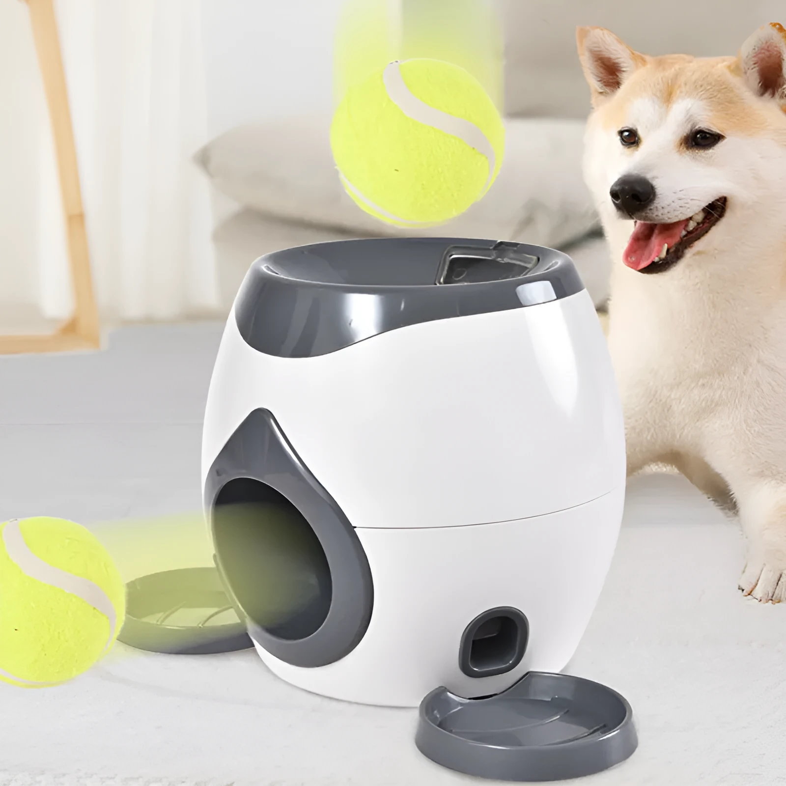Smart pet feeder reward machine with two tennis balls and treat dispenser in green and white colour, shown on a wooden floor