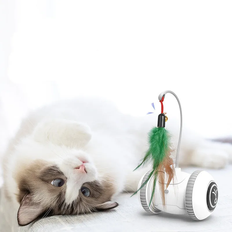 White and grey automatic interactive cat toy with interchangeable feather accessory on a floor, USB cable attached