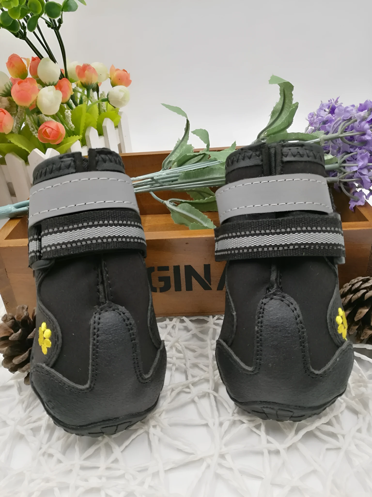 Black pet dog shoes with waterproof PVC sole and adjustable fuzzy belt on a light background