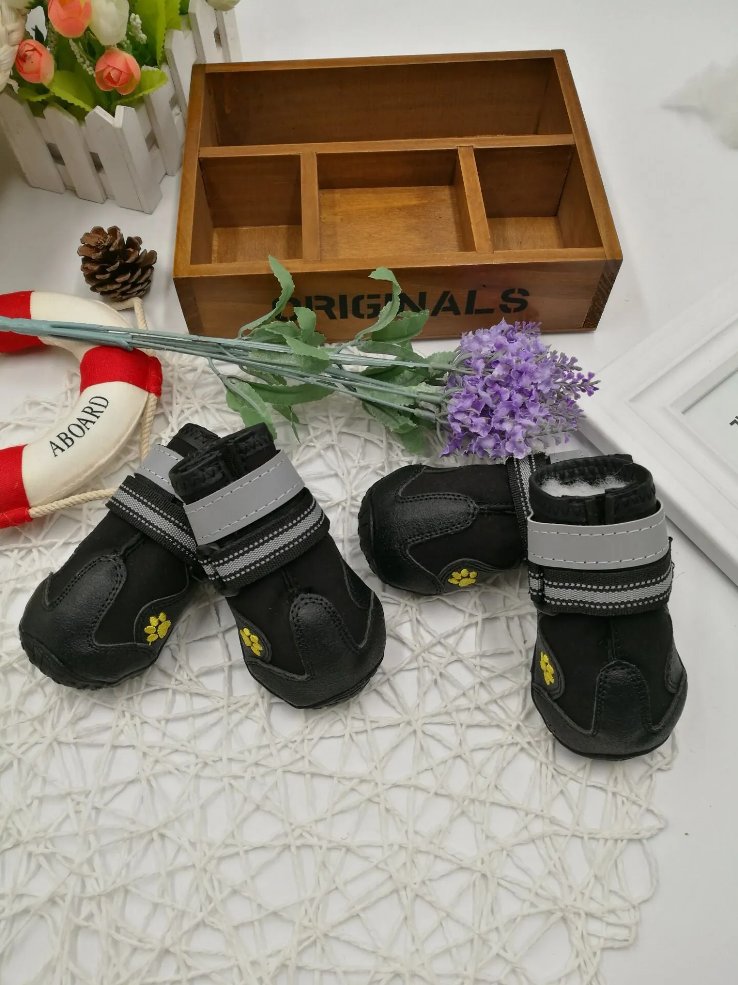 Black pet dog shoes with waterproof PVC sole and adjustable fuzzy belt on a light background