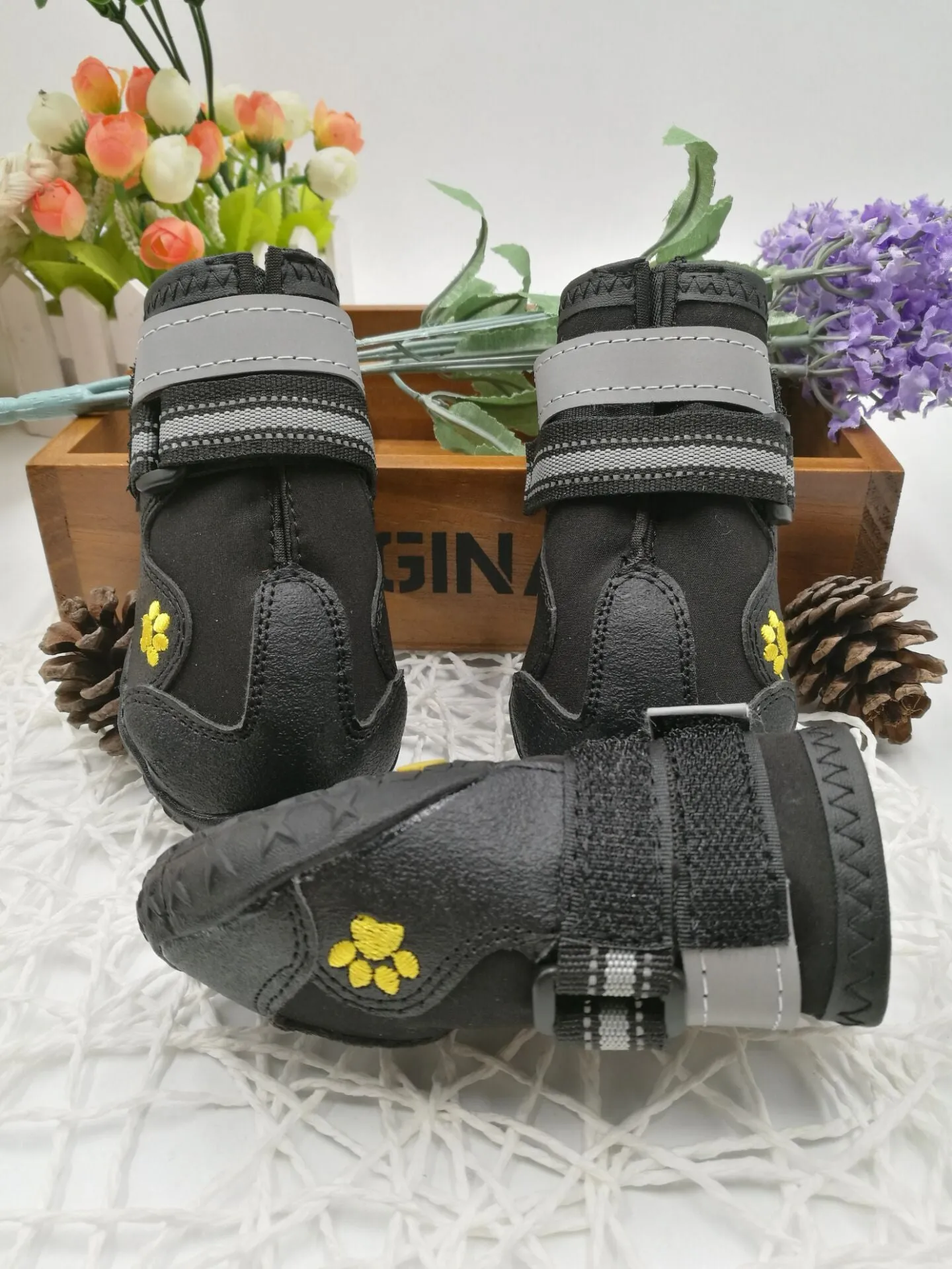Black pet dog shoes with waterproof PVC sole and adjustable fuzzy belt on a light background