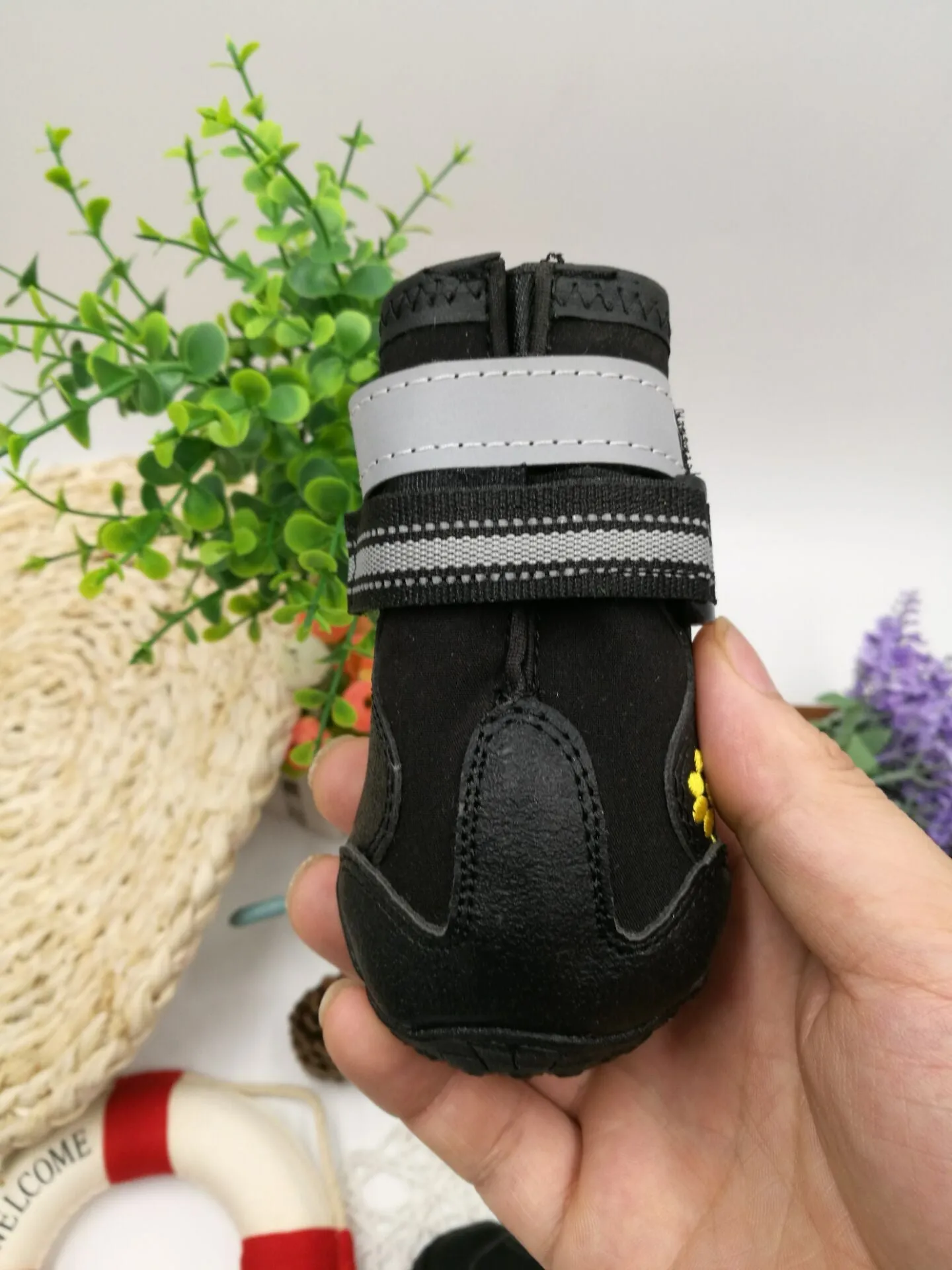 Black pet dog shoes with waterproof PVC sole and adjustable fuzzy belt on a light background