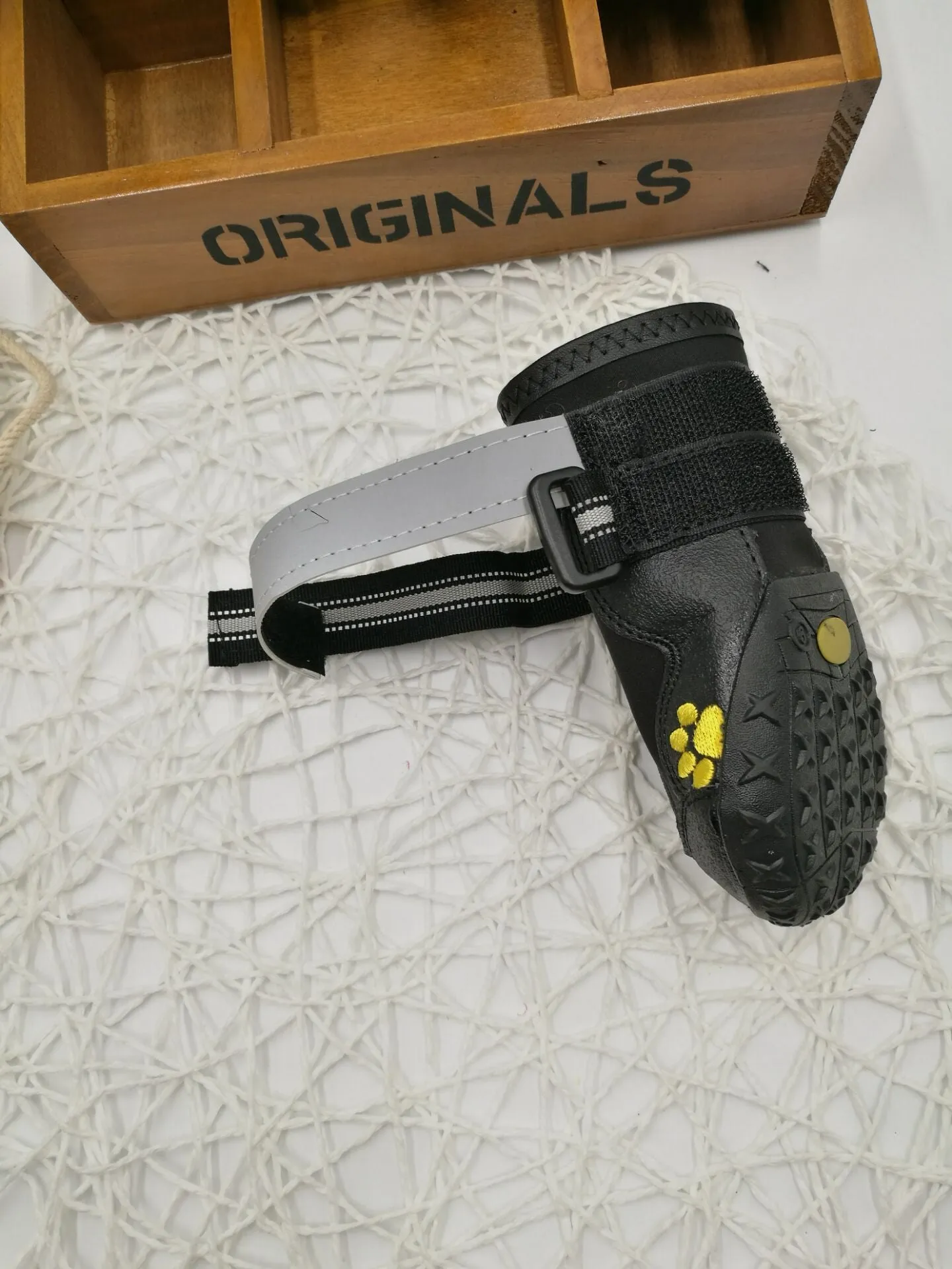 Black pet dog shoes with waterproof PVC sole and adjustable fuzzy belt on a light background