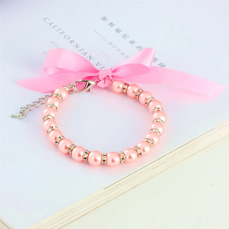 Small dog wearing adjustable pearl and rhinestone necklace with bow in blue colour