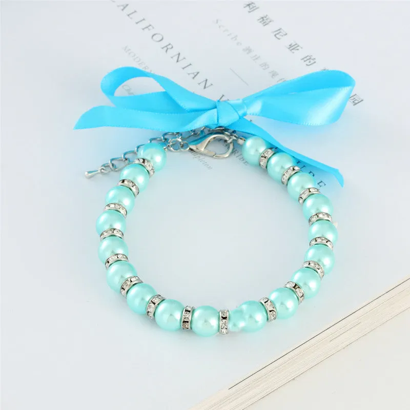 Small dog wearing adjustable pearl and rhinestone necklace with bow in blue colour