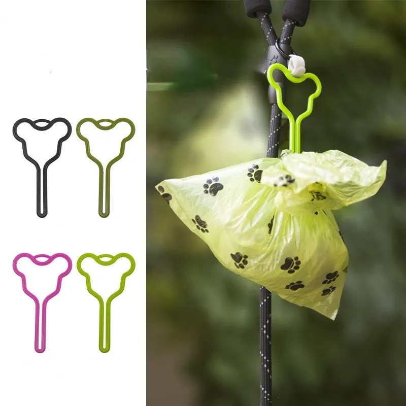 A hands-free dog poop bag holder with a fixed metal clip and a black Velcro strap for leash attachment.