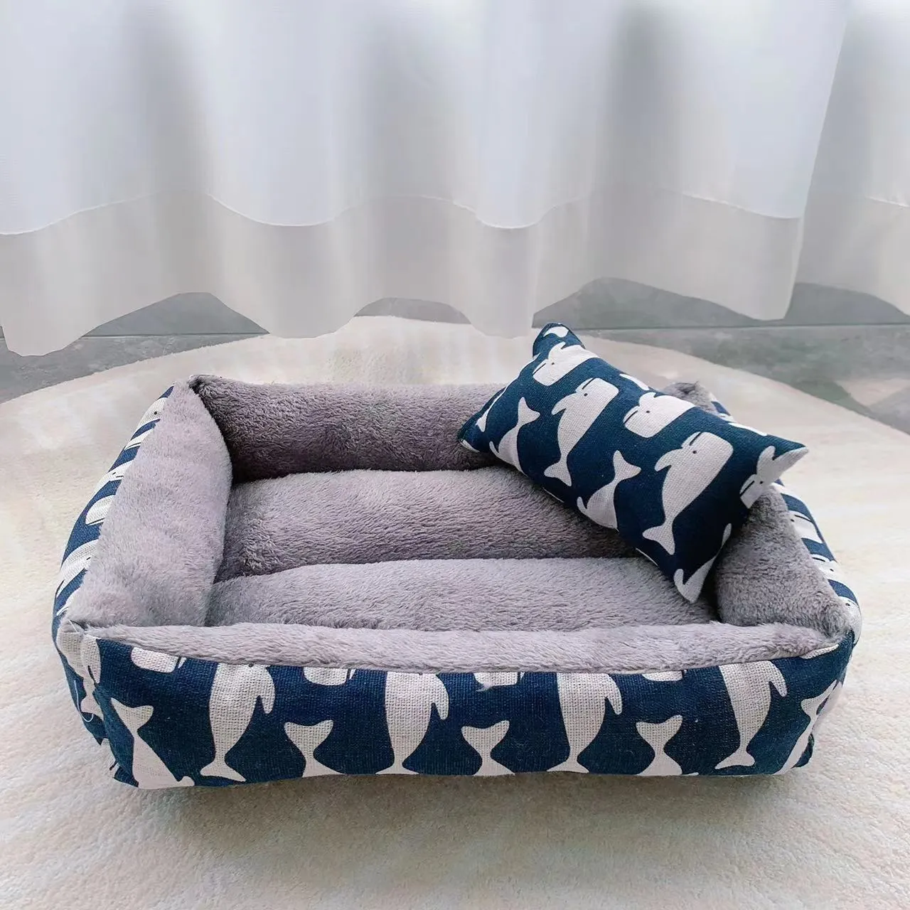 Moisture-proof linen dog bed in blue whale colour, rectangular shape with pillow, on floor.