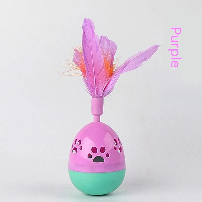 Green cat tumbler bell interactive toy with hollow footprints and feathers on a light floor