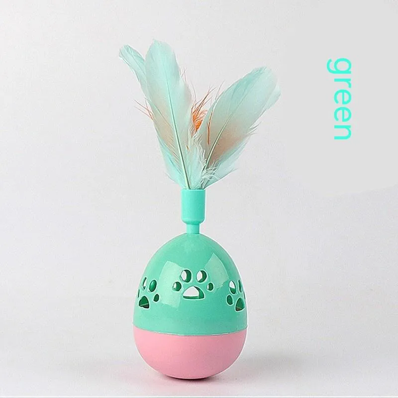 Green cat tumbler bell interactive toy with hollow footprints and feathers on a light floor