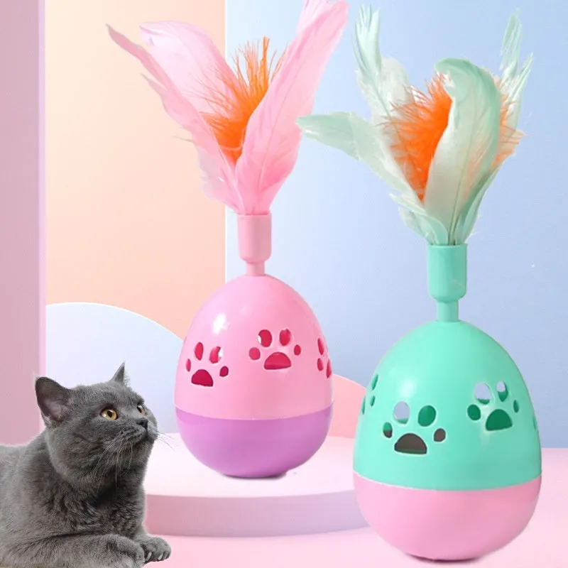 Green cat tumbler bell interactive toy with hollow footprints and feathers on a light floor