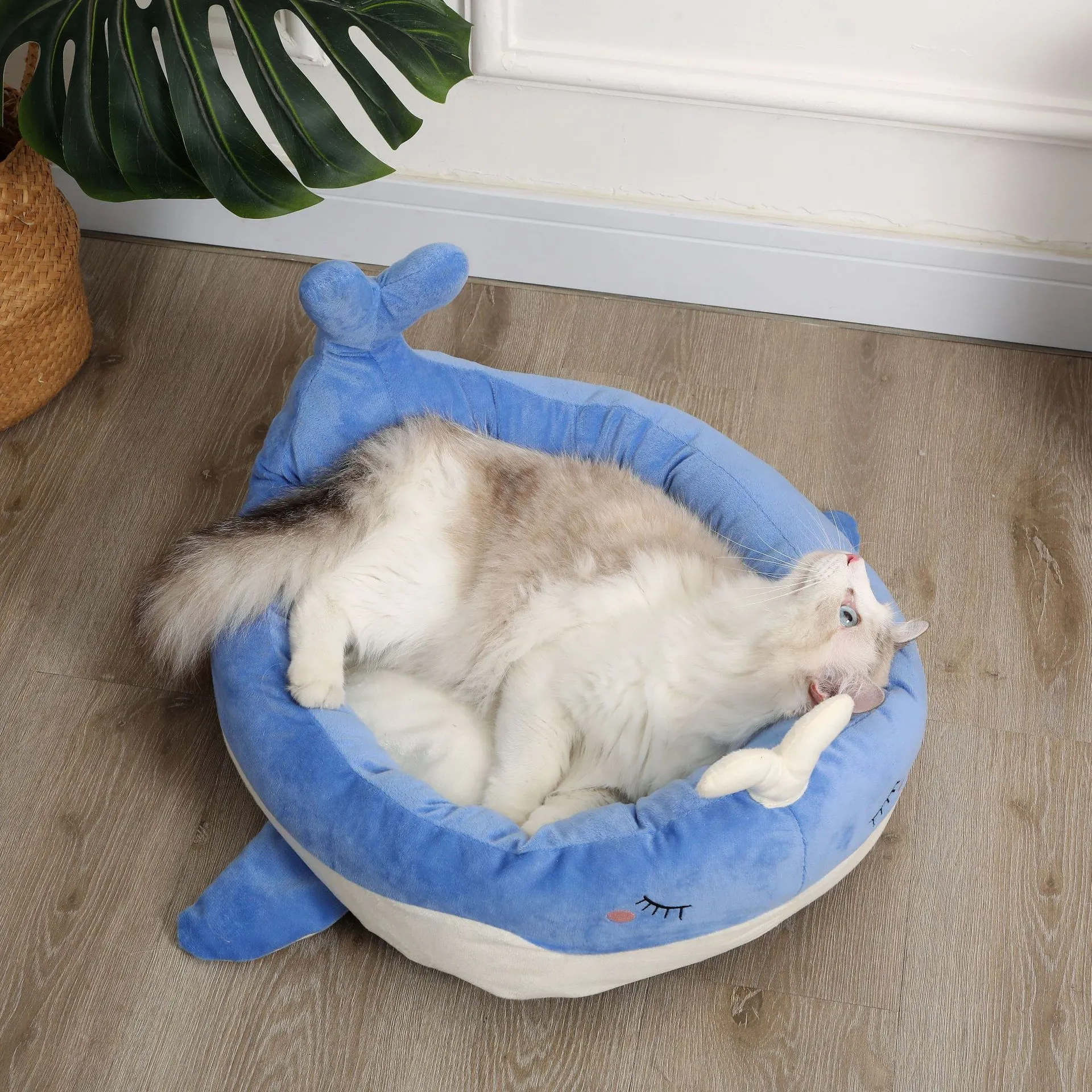 Blue duck-shaped fluffy pet bed for small dogs and cats on a wooden floor.