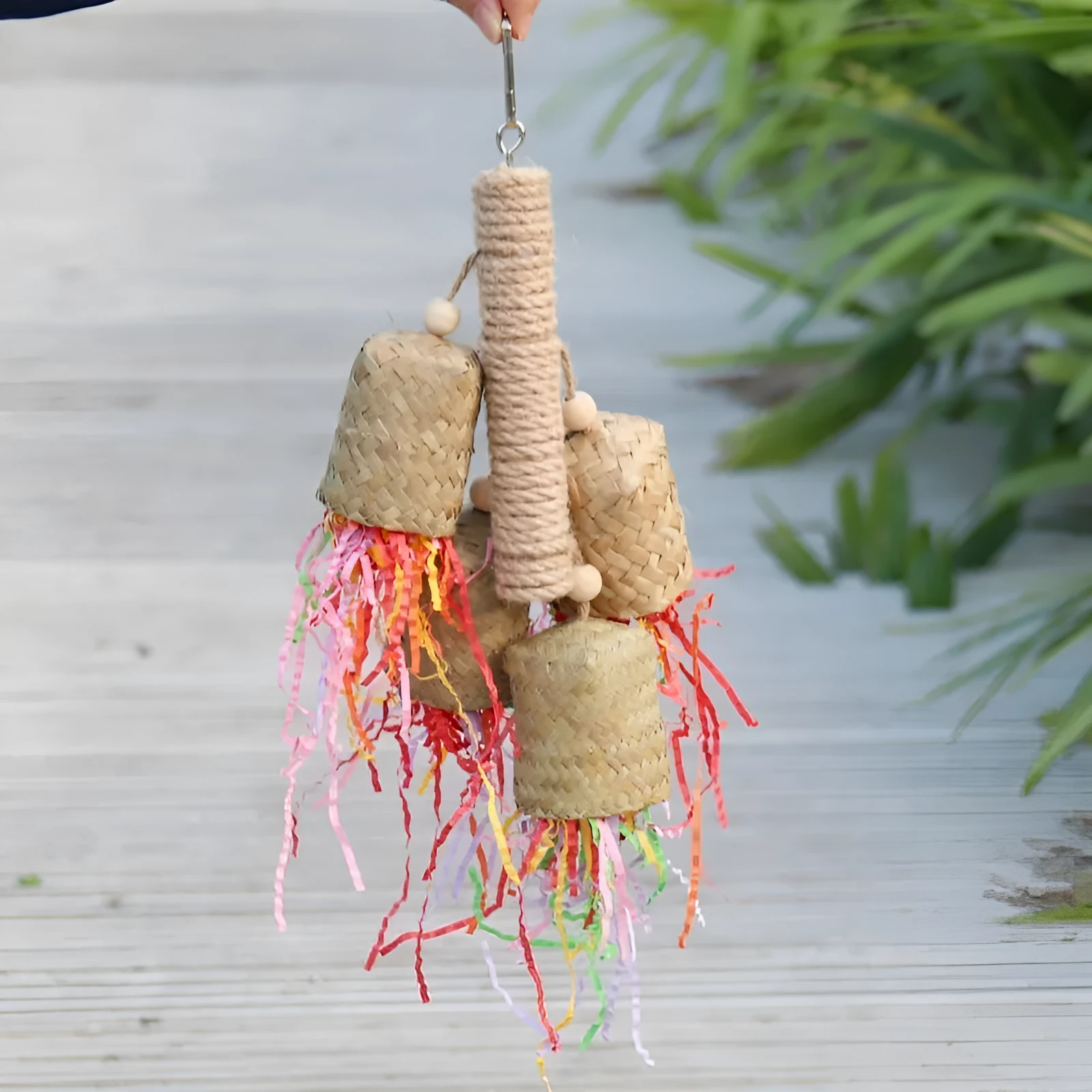 A parrot toy made of wood and sisal rope with colourful shredded paper attachments.