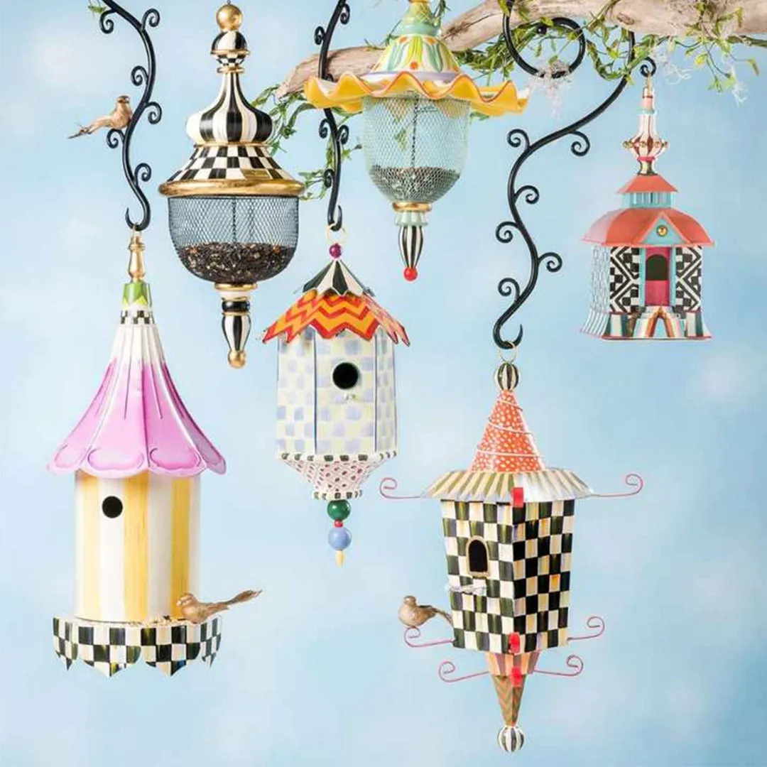 Iron metal bird feeder with creative pattern hanging from tree branch in garden