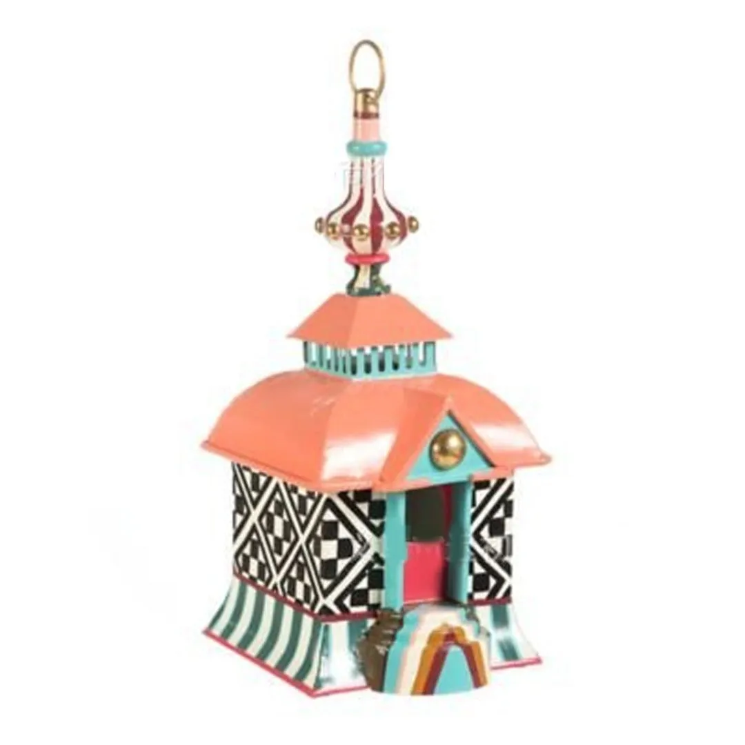 Iron metal bird feeder with creative pattern hanging from tree branch in garden