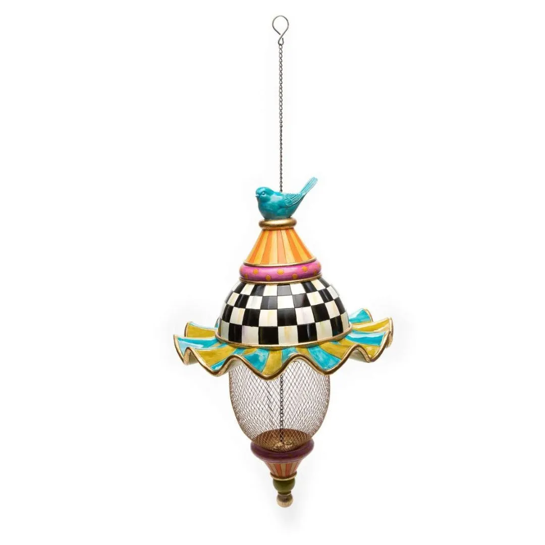 Iron metal bird feeder with creative pattern hanging from tree branch in garden